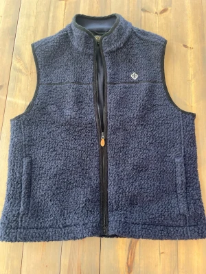 Mörkblå fleeceväst från Morris  - Skön mörkblå väst i teddyfleece och hel dragkedja framtill från Morris. Västen har två fickor och en broderad Morris logga på bröstet. Passar bra till sommar, vår, höst🤩💸  Hör av er om ni har frågor!🌟😁