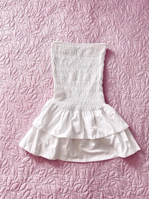 Gina Tricot - smock tube dress - Kort bandeauklänning med en smockad överdel och en utställd kjoldel med två lager volanger nedtill.   Helt oanvänd i storlek XS
