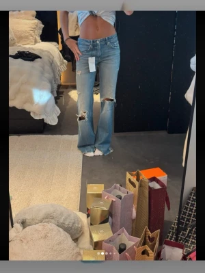 Populära Zara jeans - Säljer ett par ljusblåa bootcut jeans från Zara med slitningar och hål. Aldrig använa.