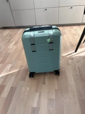  Douchebag  resvsäska  - Snygg grön resväska från  Douchebag med hårt skal och fyra hjul för smidig rullning. Väskan har ett stilrent, modernt utseende och praktiska handtag upptill. Perfekt för dig som vill resa med stil och funktion.   Helt ny nypris ligger på 4000