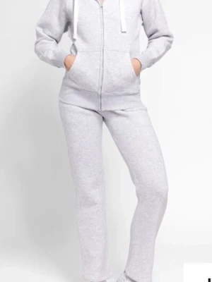 Ljusgrå mjukisbyxor med dragsko och en mjuk hoodie - Säljer ett par ljusgrå mjukisbyxor och en mjuk hoodie klassisk  modell med resår i midjan och dragsko. Byxorna har mjukt och skönt material, perfekta för chill dagar.byxorna har en såld fettfläck