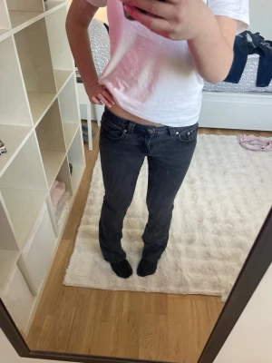 Svarta/mörkgråa bootcut jeans från gina - Säljer ett par svarta/mörkgråa bootcut jeans från gina med klassisk femficksdesign och låg midja. Jeansen har snygga detaljer på bakfickorna och är tillverkade i ett mjukt denimtyg med lite stretch för extra komfort. Perfekta för en avslappnad och trendig look. De är lite urtvättade. Storlek 38 men passar som 34/36. Nypris 500kr!