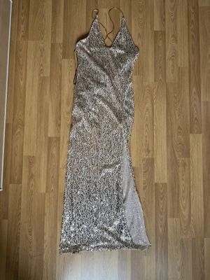  Champagne, Färg-ad paljett maxiklänning H&M -  En champagne Färg-ad Maxi, paljettklänning från H&M som har body sot knäpp under och är backless med kors band.