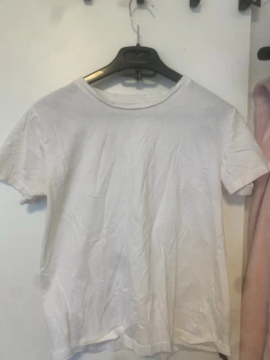 Vit basic t-shirt i bomull - Enkel vit t-shirt med rund hals och korta ärmar. Perfekt basplagg i garderoben, tillverkad i mjuk bomull. Passar till allt och är lätt att styla.
