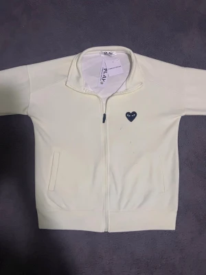 Vit zip hoodie från Comme des Garçons - Hejsan säljer en cdg zip i färgen bärsh och i storlek xs.  Den är helt ny men jag fick hem den så jag hade inte nån aning att den kom så med sånna fläckar i ljuston. Inga mer defekter på tröjan mer än de fläckarna på tröjan annars är den jätte bra skick.
