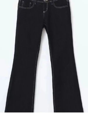 Svarta bootcut jeans med kontrastsömmar - Snygga svarta bootcut jeans med vita kontrastsömmar och klassisk femficksdesign. Jeansen har utsvängda ben och hög midja, perfekta för en trendig look. Tillverkade i denim med stretch för extra komfort.