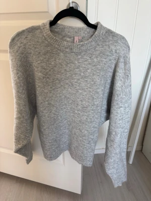 Ljusgrå stickad tröja från nelly - En enkel och stilren ljusgrå stickad tröja från Nelly med rund halsringning och långa ärmar. Tröjan är mjuk och har en klassisk passform. Sparsamt använd och fortfarande väldigt bra skick!
