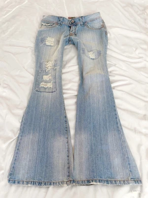 Ljusblå vintage superlågmidjade jeans med slitningar - Så snygga vintage superlågmidjade jeans! Midjemått rakt över: 40 cm Innebenslängd: 82 cm 