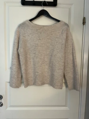 Beige stickad tröja Gina Tricot - Mysig beige stickad tröja från Gina Tricot med bred ribbad kant vid ärmslut och nederkant. Tröjan har en avslappnad passform och bred halsringning. Skulle nog säga det är storlek S