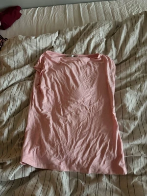 Ljusrosa basic t-shirt - En enkel ljusrosa t-shirt med rund hals och korta ärmar. Tillverkad i mjukt bomullstyg som känns skönt mot huden. Perfekt att matcha med jeans eller shorts för en avslappnad look.