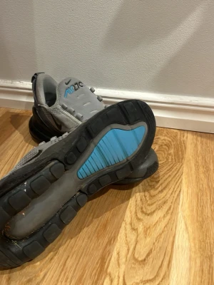 Nike Air Max 270 grå/blå sneakers äkta. - Nike Air Max 270 sneakers i grå mesh med svarta och blå detaljer. Skorna har en stor synlig Air-enhet i hälen och en blå sektion på yttersulan. Swoosh-logga på sidan och AIR270-tryck på plösen. Sköna och sportiga med modern design.
