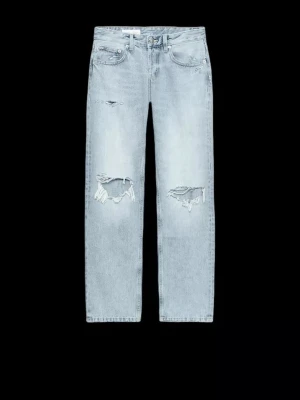 Lågmidjade ljusblå jeans med slitningar - Säljer ett par ljusblå jeans med låg midja, raka ben som sitter lite baggy och tydliga slitningar över knäna.  Perfekta för en avslappnad och trendig look. Säljer då jag köpte fel storlek och han inte lämna tillbaka. 