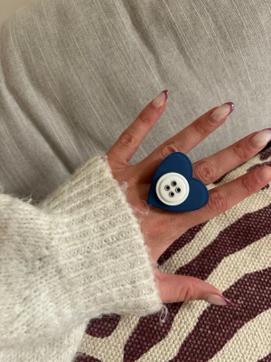 Ring med knapp - Säljer denna handgjorda ring.  Knapparna är vintage men själva ringen/ringstommen är helt ny och oanvänd. Materialet är rostfritt stål och varken tappar färg eller färgar av sig på huden. Ringen tål vatten. Storleken är justerbar, man kan trycka ihop och dra isär ringen till önskad storlek. Perfekt för dig som vill bära något unikt!