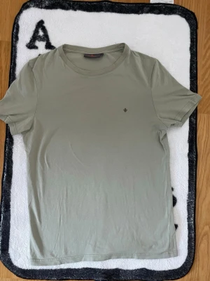 Olivgrön t-shirt från Morris - Snygg olivgrön t-shirt från Morris med diskret logga på bröstet. Klassisk rund halsringning och korta ärmar. Tillverkad i mjuk bomull som känns skön mot huden. Perfekt basplagg för en clean och stilren look.