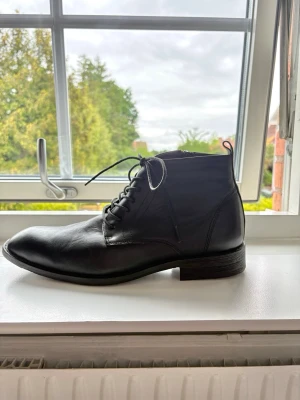 Svarta klassiska läderstövletter - Säljer ett par svarta stövletter i äkta läder med snörning och låg klack. Skorna har en stilren och tidlös design som passar till många olika outfits. Perfekta för dig som gillar en clean och klassisk look. Storleken är inte helt klarlagd men kolla bilderna, uppskattningsvis storlek 43. Köpt för 89.99 euro. 