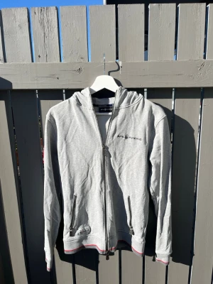 Ljusgrå zip hoodie från Sail Racing - Ljusgrå zip hoodie från Sail Racing i storlek M. Mycket bra skick, använd några gånger. Hör av dig vid frågor eller funderingar!