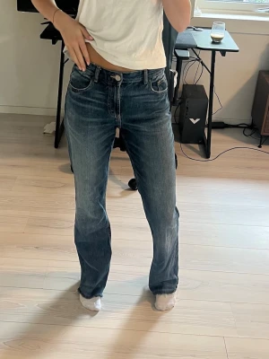 Blå raka jeans med vintagekänsla - Säljer ett par blå jeans med rak passform och klassisk femficksdesign. Jeansen har en snygg tvättad look och normal midja. Perfekta för dig som gillar en avslappnad men ändå stilren vibe. Materialet är denim i bomull.