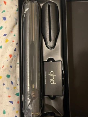 ghd V Gold Professional Styler - ghd V Gold Professional Styler är en svart plattång med elegant design och gulddetaljer. Perfekt för att styla håret rakt eller lockigt. Kommer i originalförpackning med värmeskydd och tillbehör. Tillverkad i högkvalitativt material för professionellt resultat.