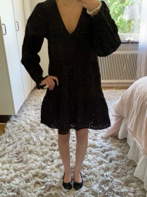 Svart kort klänning med v-ringning ifrån hm💓💓 - Säljer en svart kort klänning med v-ringning och långa puffärmar. Klänningen har broderade detaljer och små hålmönster. Den är ganska så stor på mig det är därför jag säljer den. Den är ifrån hm i storlek xs/34💓💓