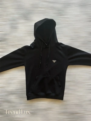 Prada Hoodie - Svart hoodie från Prada. Väldigt stiligt och snyggt passar bäst för dig som vill gå runt med stil. Denna underbara hoodien har inga skador/defekter alls. Med minsta lilla fundering tveka inte på att höra av er