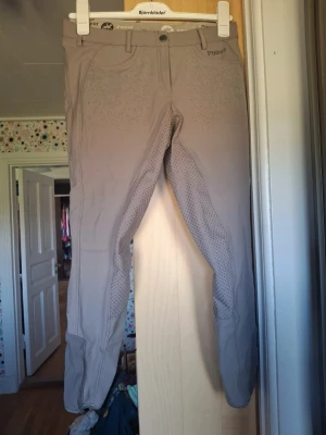 Helskodda ridbyxor från pikeur - Helskodda ridbyxor med fina detaljer i fram och ibak. Är i en lila/beige färg. Använda några gånger men är för korta för mig. Storlek 40 Skriv om ni vill ha mer info, mått eller bilder! 