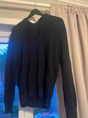 Mörkblå cashmere hoodie Sayless - Mysig mörkblå stickad hoodie från Sayless i mjuk cashmere. Tröjan har huva med dragsko och långa ärmar, perfekt för en chill och stilren look. Passar dig som gillar både komfort och enkel design.
