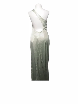Ljusgrön one shoulder långklänning - Elegant ljusgrön långklänning i glansigt material med one shoulder-design och öppen rygg. Klänningen har en figurnära passform och är perfekt för dig som vill sticka ut med en stilren look.