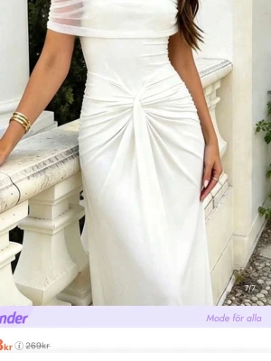Vit offshoulder långklänning - Elegant vit långklänning med offshoulder och draperad detalj framtill. Klänningen har en figurnära passform och är tillverkad i ett mjukt, stretchigt material som ger en snygg siluett. Perfekt för speciella tillfällen när du vill sticka ut.