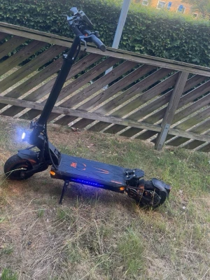 Kukirin g2 manster - Säljer en svart el-scooter med coola LED-lampor på sidorna och framlyse. Scootern har orange detaljer och bred ståplatta med mönster. Utrustad med stora hjul och robust ram, perfekt för att ta sig runt i stan på ett smidigt sätt. Det finns mycket utrustning på den för att skydda den av Sten skot och annat 