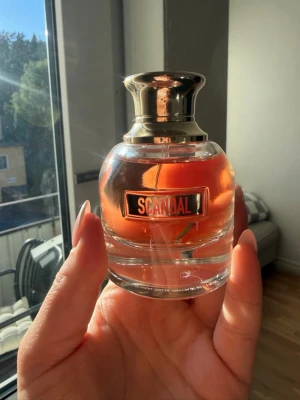 Scandal parfym från Jean Paul Gaultier 30ml - Scandal parfym från Jean Paul Gaultier i en rund glasflaska med guldig metallkork. Flaskan har en elegant design och innehållet är i en varm rosa-orange nyans. Perfekt för dig som gillar lyxiga och unika dofter. Ej använd