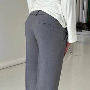 Grå bootcut kostymbyxor - Snygga grå kostymbyxor med bootcut-snitt och pressveck framtill. Perfekta för en clean och stilren look, passar till både skjorta och t-shirt. Materialet är mjukt och har en lätt struktur.