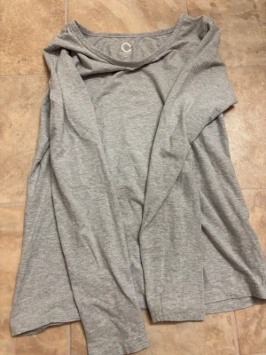 Ljusgrå långärmad tröja - En basic ljusgrå långärmad tröja från Cubus i mjukt och tunt bomullsmaterial. Tröjan har rund halsringning och en avslappnad passform, perfekt att matcha med jeans eller kjol.