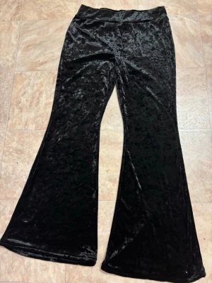 Svarta utsvängda sammetsleggings - Snygga svarta leggings i mjuk sammet med utsvängda ben. Perfekta för dig som gillar en trendig och bekväm stil. Stretchigt material som sitter skönt hela dagen.