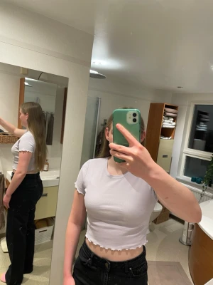 Ljuslila croppad ribbad topp - Trendig ljuslila croppad topp med ribbad struktur och vågiga kanter vid ärmslut och nederkant. Kortärmad modell med rund halsringning, perfekt att styla med höga jeans eller kjol. Superfin färg som poppar i garderoben!