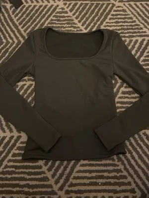 Svart långärmad topp med fyrkantig ringning - En stilren svart långärmad topp med fyrkantig ringning. Toppen har en tight passform och är fodrad som en fleece inuti. Säljer då den är för liten men är i bra skick. Tveka inte på att höra av dig för fler frågor eller bilder🤗