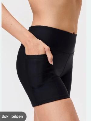 Svarta träningstights shorts/padelshorts - Snygga svarta träningstights shorts med hög midja och praktiska sidofickor. Tillverkade i stretchigt syntetmaterial som sitter tight och bekvämt. Perfekta för gymmet eller löprundan.