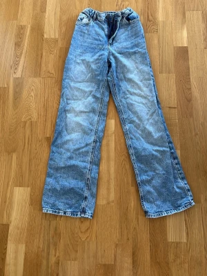Blå raka jeans från Lindex - Snygga ljusblå jeans från Lindex med klassisk femficksdesign och raka ben. Jeansen har normal passform och är tillverkade i mjukt bomullsmaterial med en lätt tvättad look. Perfekta för dig som gillar enkel och stilren denim.