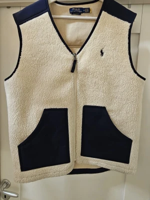 Fleeceväst från Polo Ralph Lauren - Snygg fleeceväst från Polo Ralph Lauren med den klassiska broderad loggan på bröstet. Västen är sparsamt använd, ca 3 gånger. Säljer den på grund av att västen är lite stor på mig och där med svårt att använda den. Han jag köpte den ifrån köpte den direkt ifrån Ralph lauren. Nypris 2600
