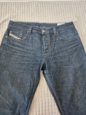 Vintage Diesel jeans  - Snygga blå vintage jeans från Diesel med klassisk femficksdesign och kontrastsömmar. Jeansen har en rak passform och detaljerad logga på myntfickan. Perfekta för dig som gillar en tidlös och stilren look.
