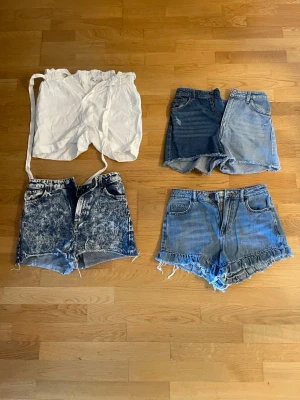 Fyra par shorts i olika denimstilar - Fyra par shorts: ett vitt med snörning i midjan, tre i olika blå denimtvättar. Ett par är acid wash, ett har råa kanter och ett är klassiskt ljusblått. Perfekta för sommaren och enkel styling.  Det är olika märken och kan variera lite i storlek men inte mycket. Det är 40 kr styck