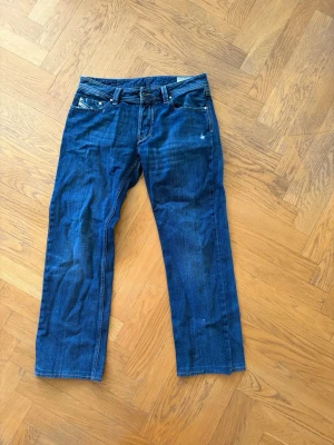 Blå raka jeans från Diesel Larkee - Ett par blåa Diesel jeans. Strlk W34, L34. Uppsydda till en L32 (se bilder) som antingen behöver sys om eller så kommer de lossna. Kommer se ut som på sista bilden isf.