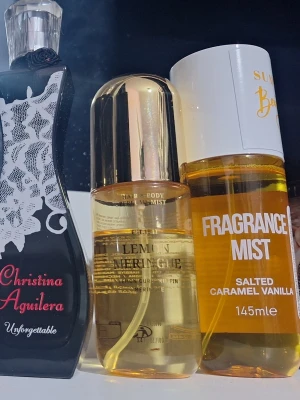 Mix av 6 parfymer och body mists - Säljer ett set med 6 olika parfymer och body mists. Inkluderar Christina Aguilera Unforgettable (svart flaska med spetsmönster), La Rive Destinee (transparent flaska), samt dofter som Salted Caramel Vanilla, Lemon Meringue och Amber Sandalwood. Färgerna varierar från guld till rosa och bärnstensfärgat.