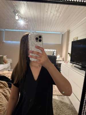 Svart v-ringad topp från Wera - En svart, mjuk och luftig topp från Wera med v-ringning och korta ärmar. Enkel och stilren som passar perfekt till jeans eller kjol. Säljs pga: använder inte längre. 