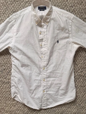 Vit skjorta från Polo Ralph Lauren🙌🤩 - Klassisk vit skjorta från Polo Ralph Lauren med button-down krage och broderad logga på bröstet. Skjortan har långa ärmar och knäppning framtill. Perfekt till en stilren och tidlös look.🙌🤩