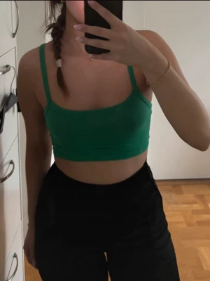 Snyggt croppat linne - Snygg grön croppad linnetopp med smala axelband och enkel, stilren design. Toppens material känns mjukt och stretchigt, vilket gör den super bekväm att bära. Passar även en xs. 