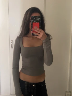 Grå långärmad croppad topp - Snygg grå långärmad topp och croppad passform. Perfekt att styla med låga jeans eller kjol för en trendig look. Det är XXS men kommer större i storlek och den är stretchig