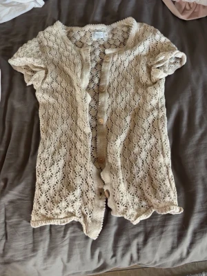 Beige virkad kofta med kort ärm - Söt beige kofta i virkad stil med korta ärmar och knappar framtill. 