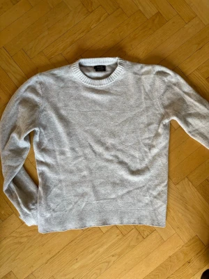 Ljusgrå stickad tröja från Massimo dutti  - Säljer en stilren ljusgrå stickad tröja från Massimo dutti. Tröjan har rund halsringning, långa ärmar och ribbade muddar vid ärmslut och nederkant. Perfekt basplagg i mjukt material som passar till det mesta.