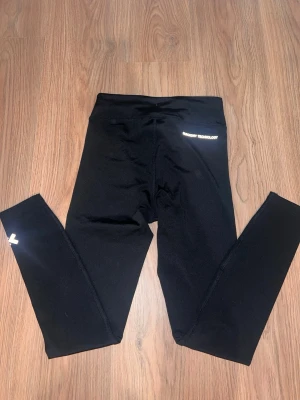 Svarta träningsleggings 157 Small - Säljer ett par svarta träningstights från 157 med logga på benet och vid midjan. Tillverkade i stretchigt funktionsmaterial som passar perfekt till gymmet eller löpning. Tight passform och hög midja för extra komfort. 100kr st 200 för båda 