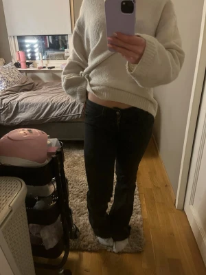 Svarta bootcut jeans - Säljer ett par svarta bootcut jeans med klassisk femficksdesign och normal midja. Jeansen har en enkel knappstängning och raka ben som smalnar av något nedtill. Perfekta för en avslappnad och trendig look.